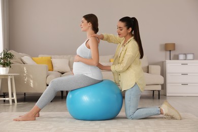 Photo of Doula working with pregnant woman in living room. Preparation for child birth