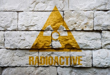 Image of Radioactive sign on white brick wall. Hazard symbol