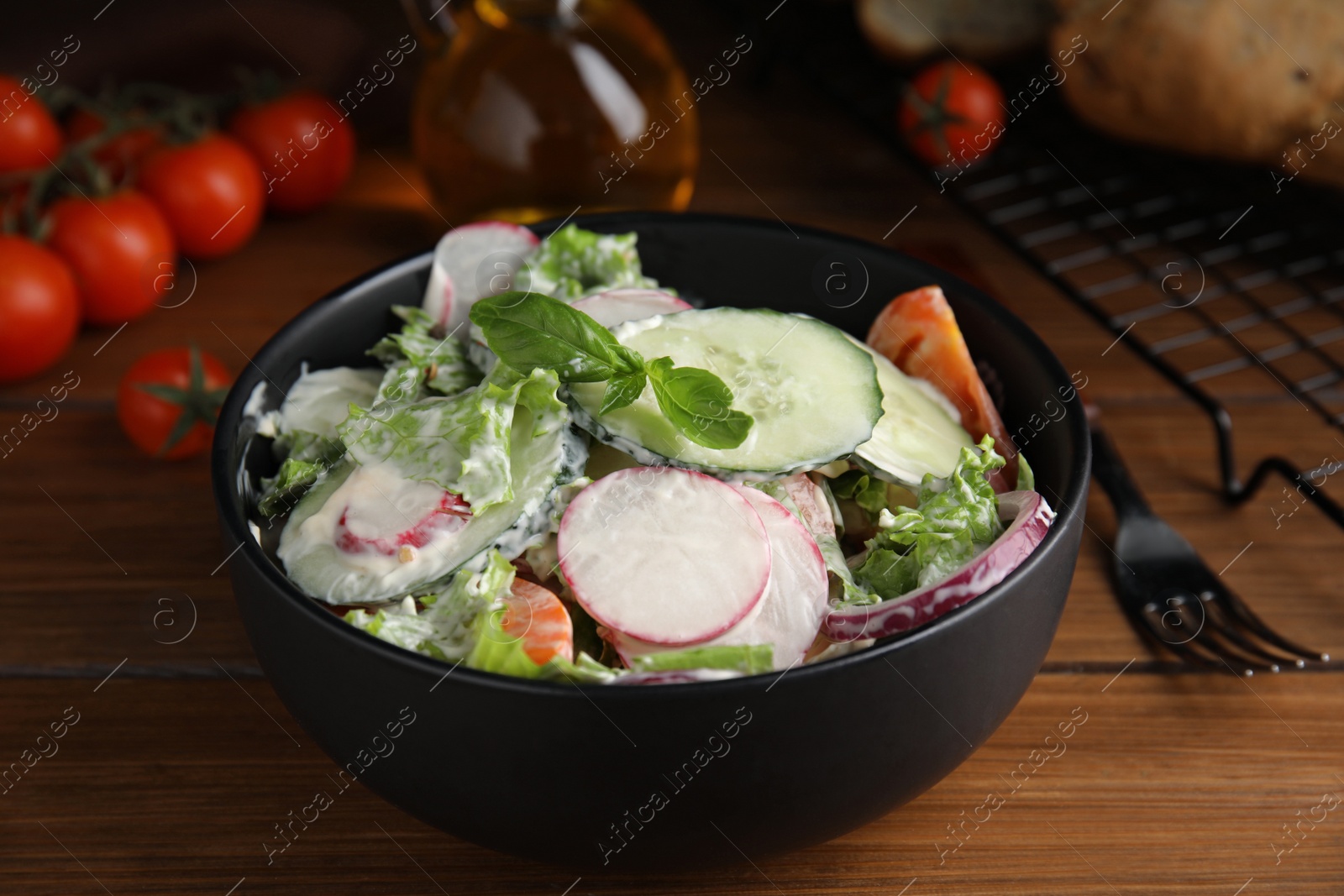 Photo of Bowl of delicious vegetable salad dressed with mayonnaise on wooden table, closeup