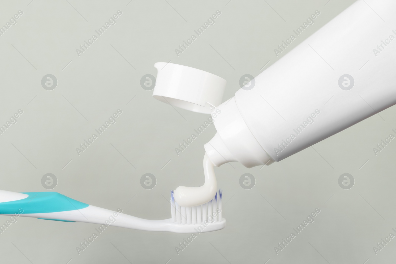 Photo of Applying paste on toothbrush against grey background