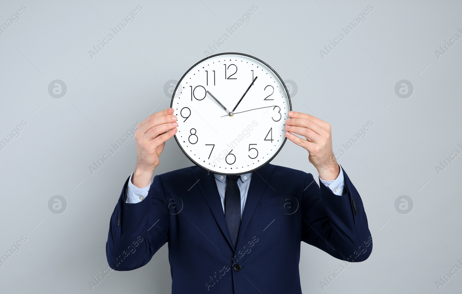 Photo of Businessman holding clock on grey background. Time management