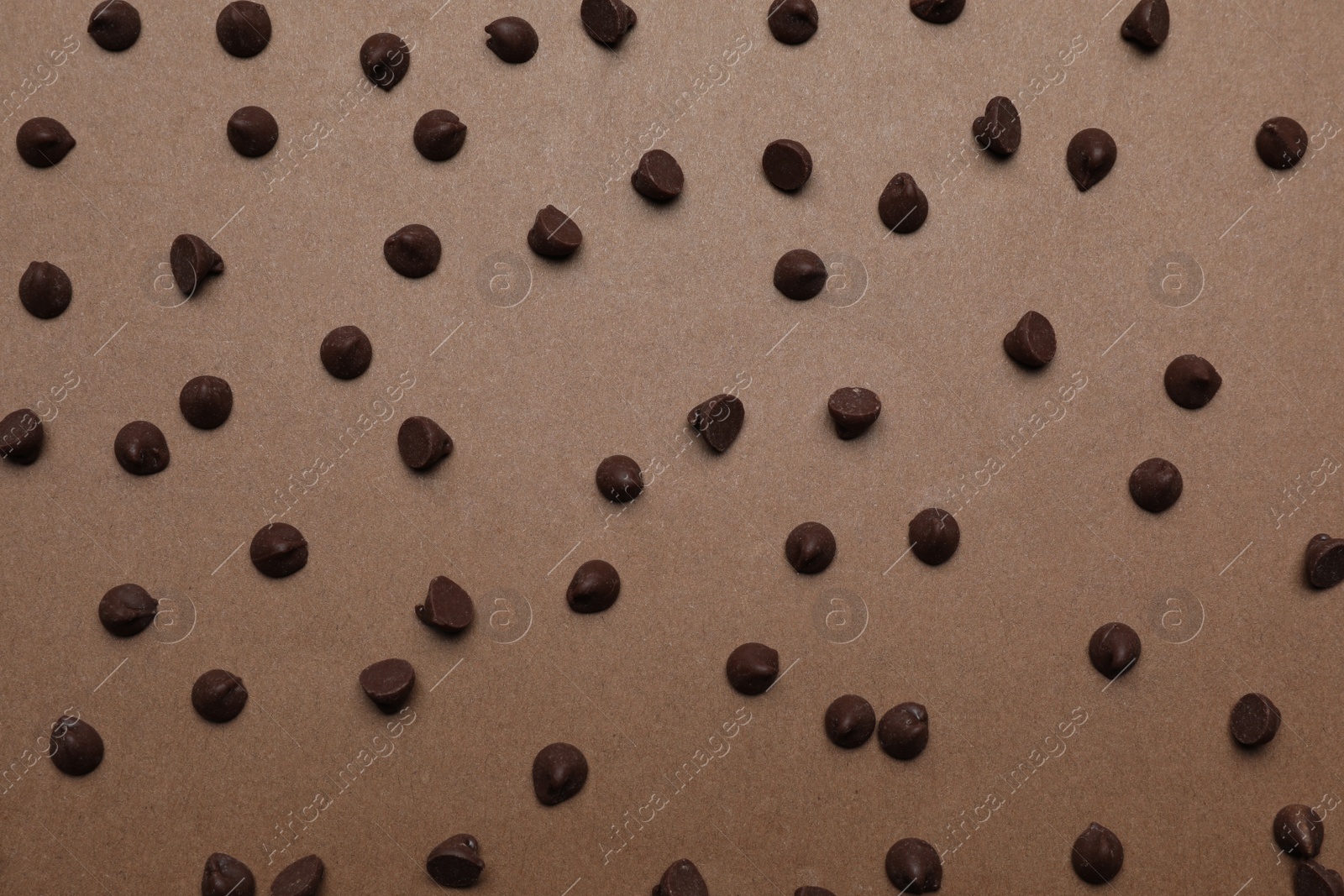 Photo of Delicious chocolate chips on brown background, top view