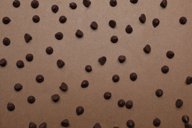 Photo of Delicious chocolate chips on brown background, top view