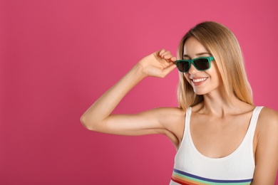 Photo of Beautiful woman in stylish sunglasses on pink background. Space for text