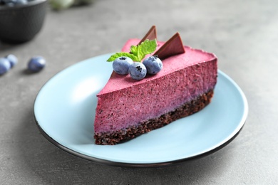 Plate with piece of tasty blueberry cake on gray table