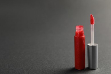 Photo of Red lip gloss with applicator on dark background. Space for text