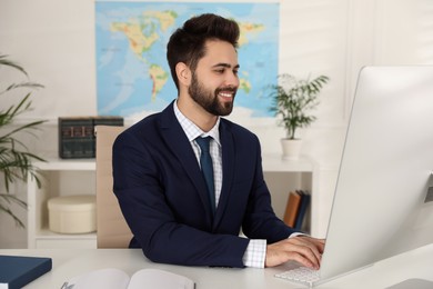 Photo of Happy manager working with computer at desk in travel agency