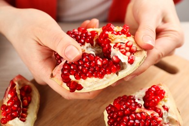 Photo of Woman with delicious ripe pomegranate at wooden table, closeup