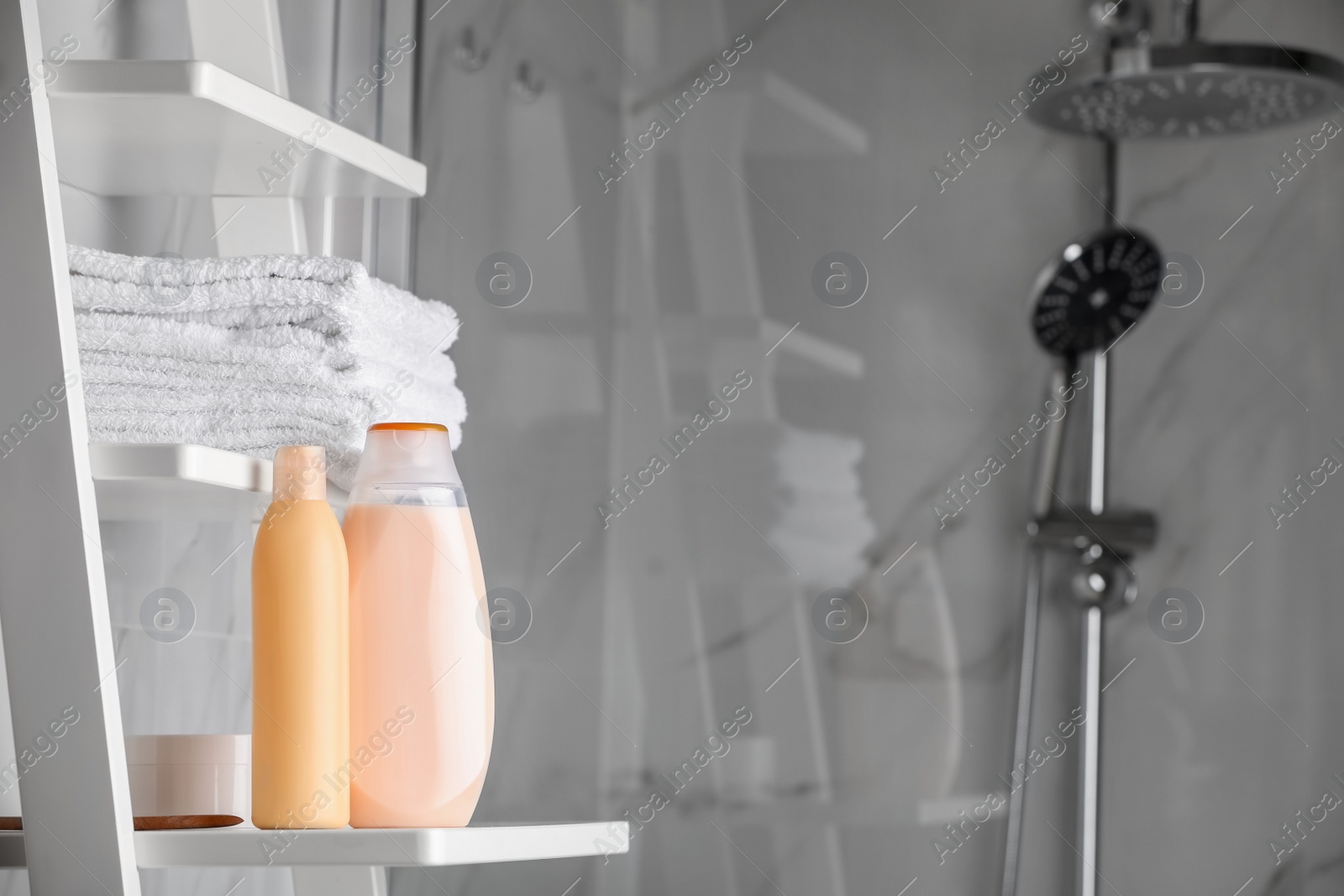 Photo of Shampoo, conditioner and towels on shelves near shower stall in bathroom, space for text