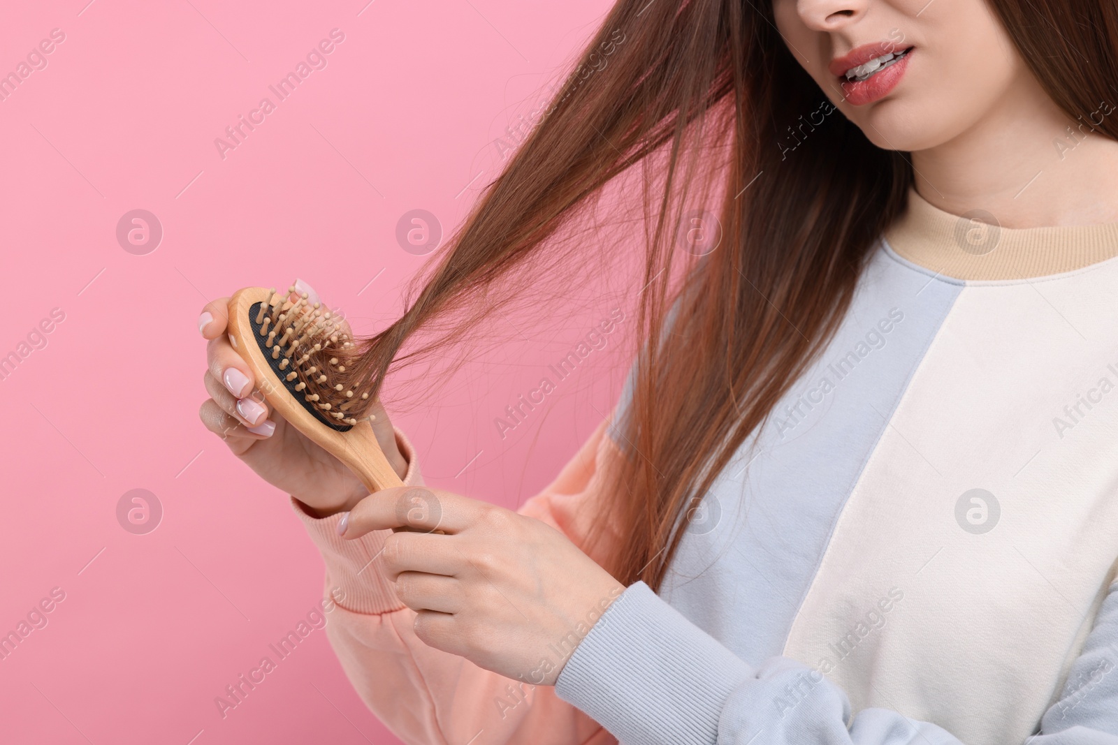 Photo of Woman brushing her hair on pink background, closeup. Alopecia problem