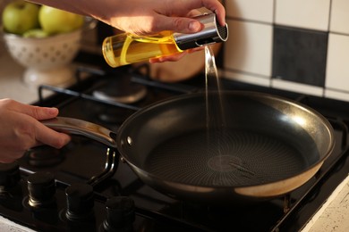 Photo of Vegetable fats. Woman sprinkling oil into frying pan on stove, closeup