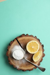 Photo of Baking soda and lemons on turquoise background, top view. Space for text