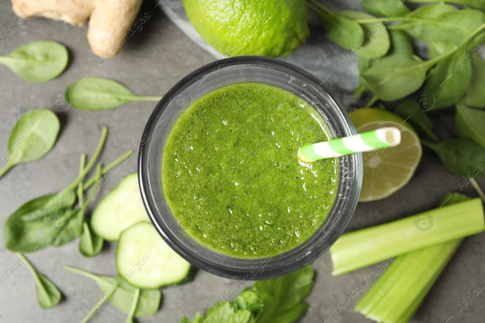 Photo of Green juice and fresh ingredients on grey table, flat lay