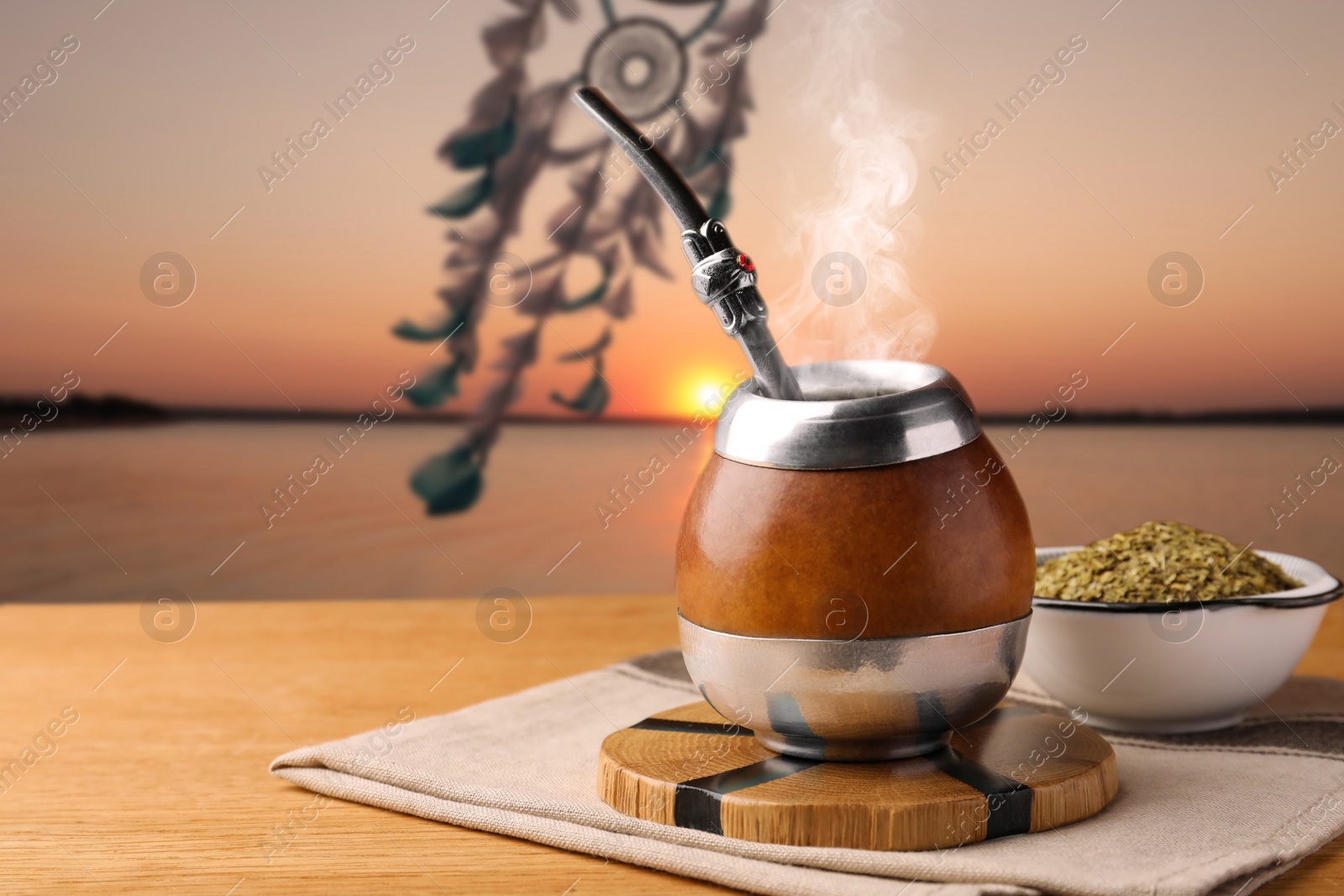 Image of Calabash with mate tea and bombilla on wooden table outdoors at sunset. Space for text