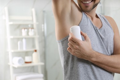 Man applying deodorant in bathroom, closeup. Space for text