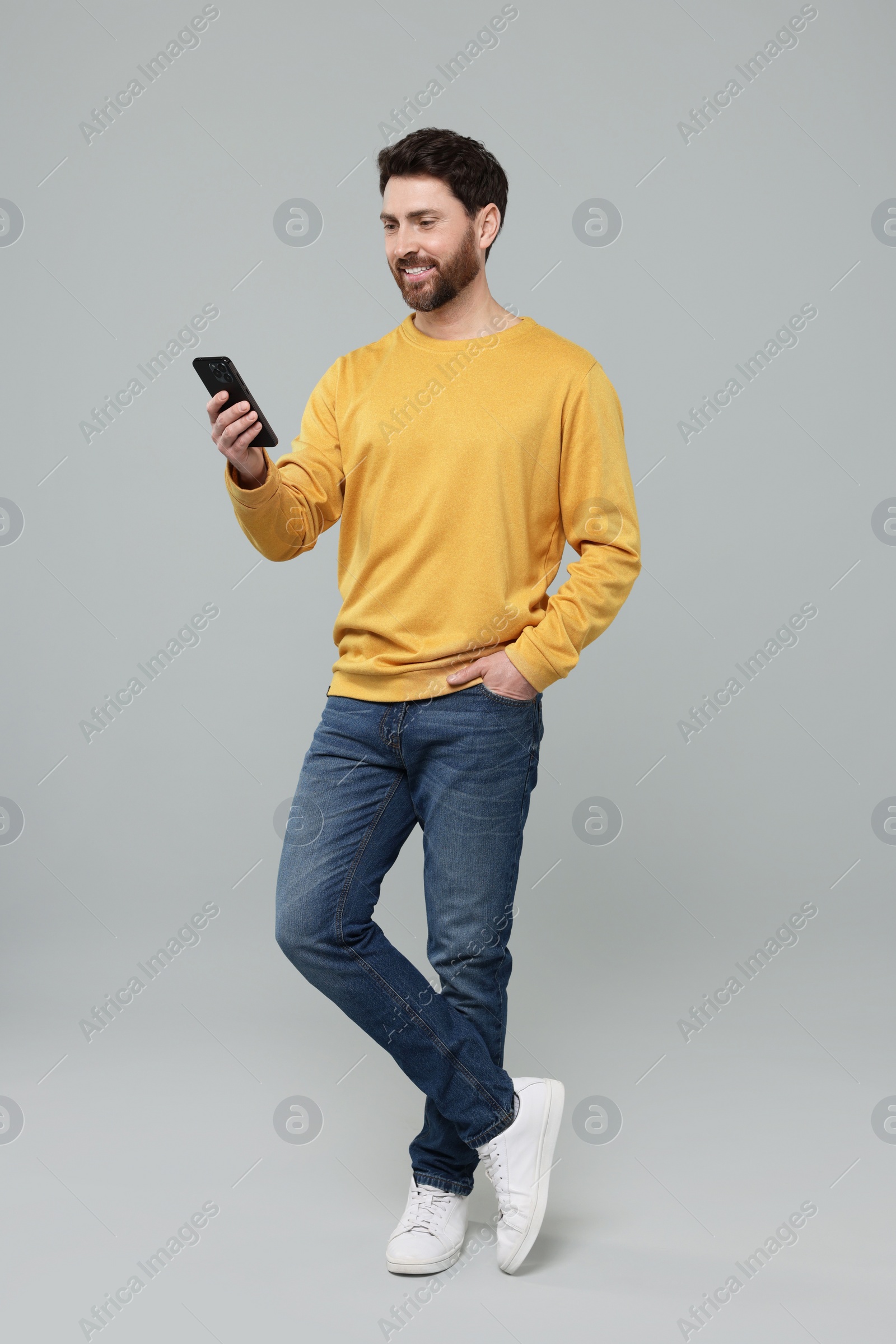 Photo of Smiling man with smartphone on grey background