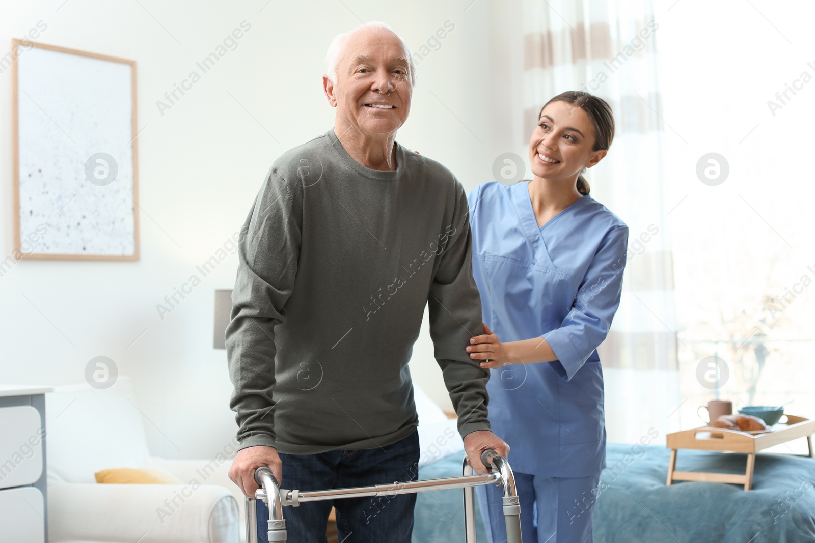 Photo of Care worker helping elderly man with walker in geriatric hospice