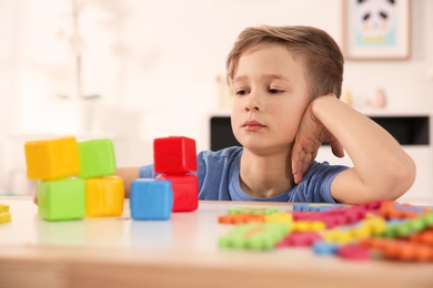 Little autistic boy playing with cubes at home