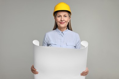 Photo of Architect in hard hat with draft on grey background