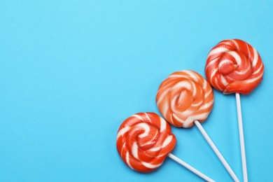 Photo of Sweet lollipops on light blue background, flat lay. Space for text