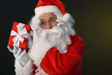 Photo of Santa Claus with Christmas gift on dark background