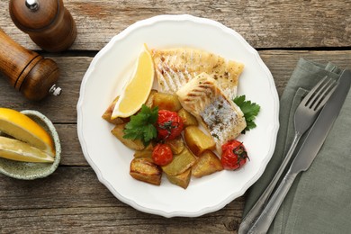 Tasty cod cooked with vegetables served on wooden table, flat lay