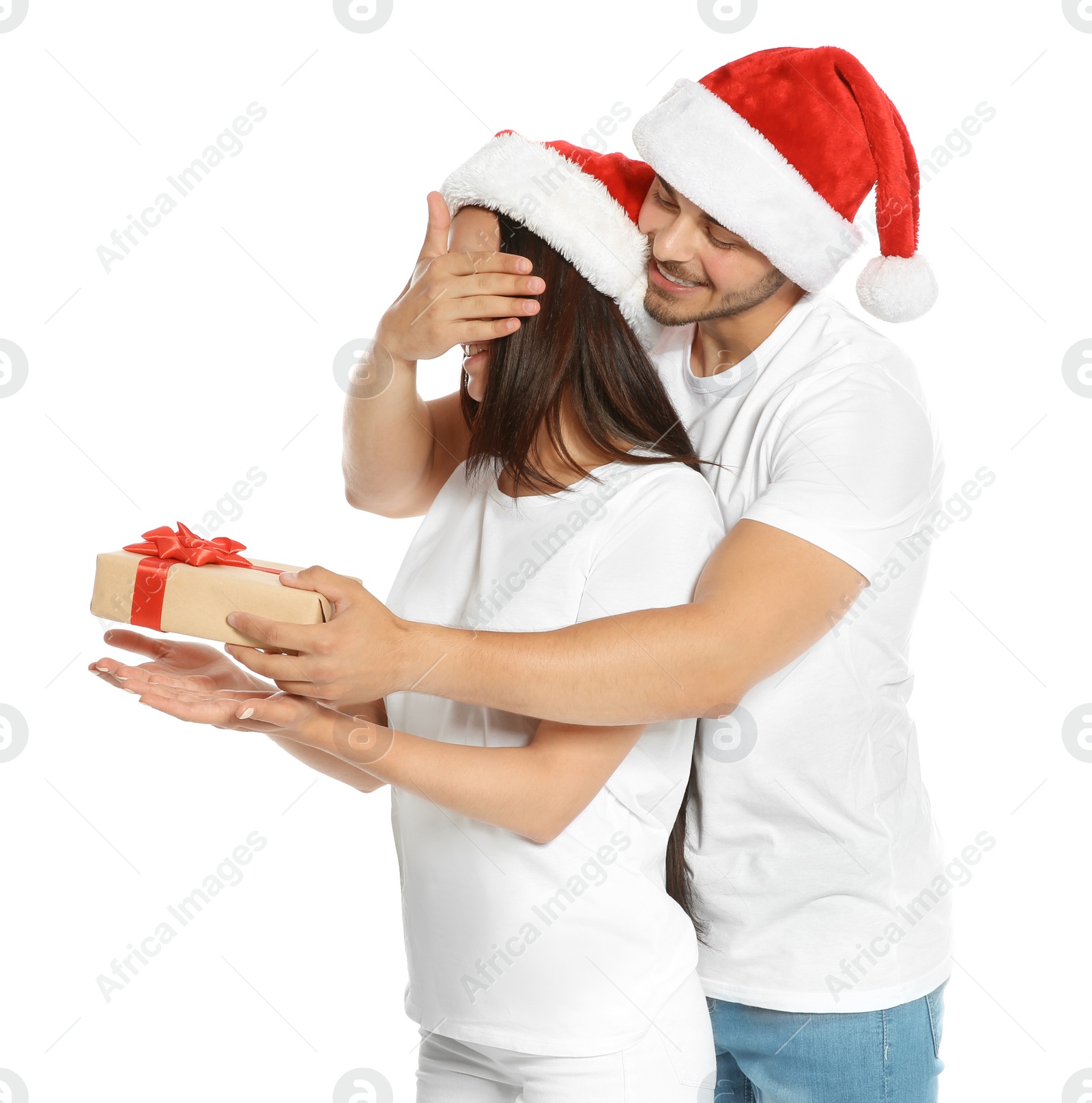 Photo of Young man giving gift box to girlfriend on white background. Happy couple celebrating Christmas