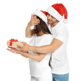 Photo of Young man giving gift box to girlfriend on white background. Happy couple celebrating Christmas