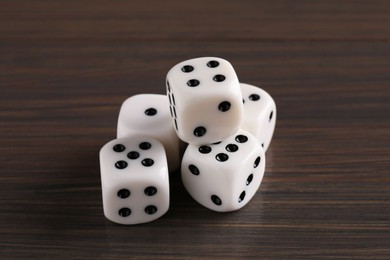 Photo of Many white game dices on wooden table, closeup