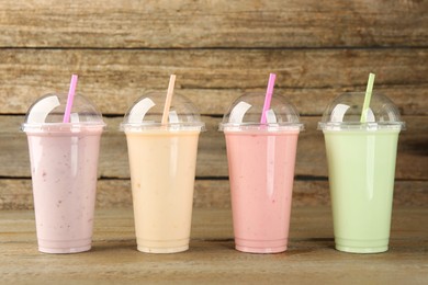 Plastic cups with different tasty smoothies on wooden table