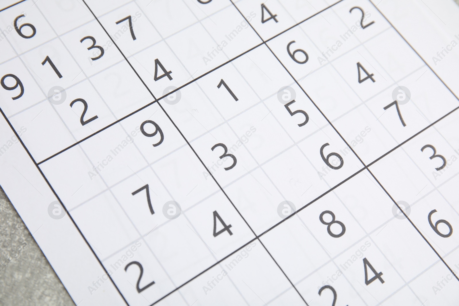 Photo of Sudoku puzzle on grey table, closeup view