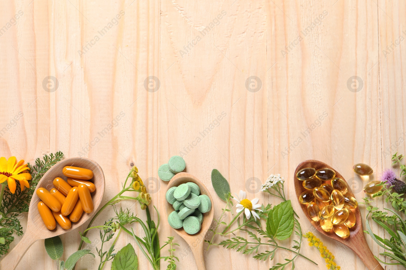 Photo of Different pills, herbs and flowers on wooden table, flat lay with space for text. Dietary supplements
