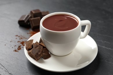 Photo of Yummy hot chocolate in cup on dark table
