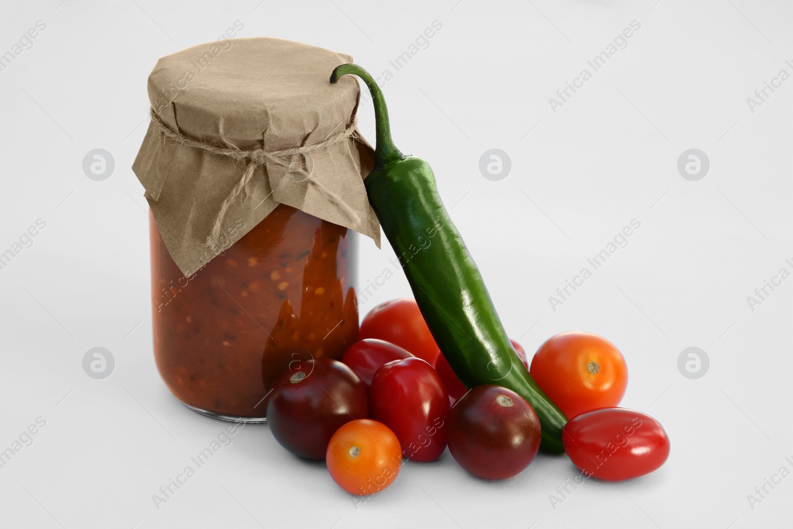 Photo of Jar with delicious salsa sauce and ingredients on white background