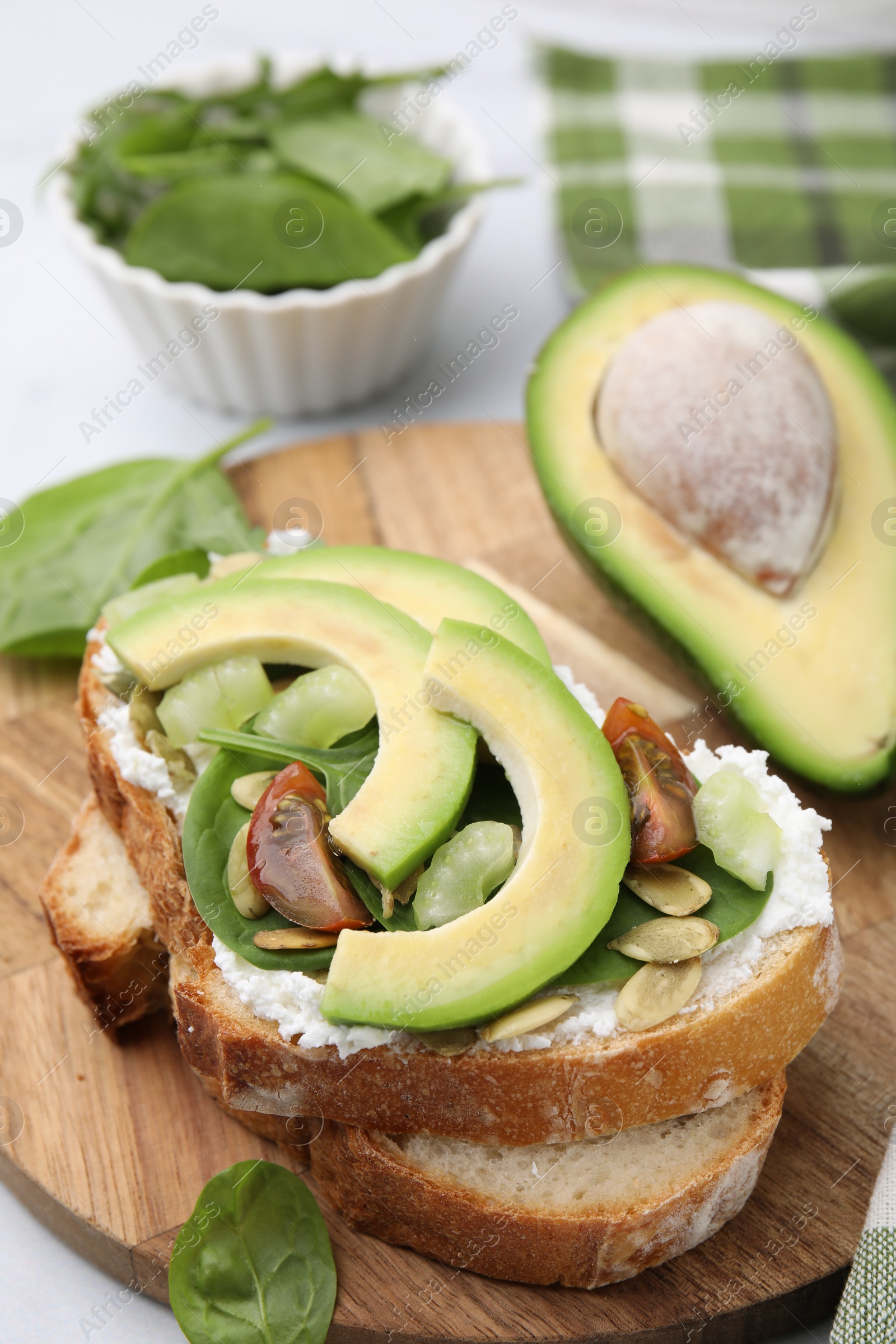 Photo of Tasty vegan sandwich with avocado, tomato and spinach on white table, closeup