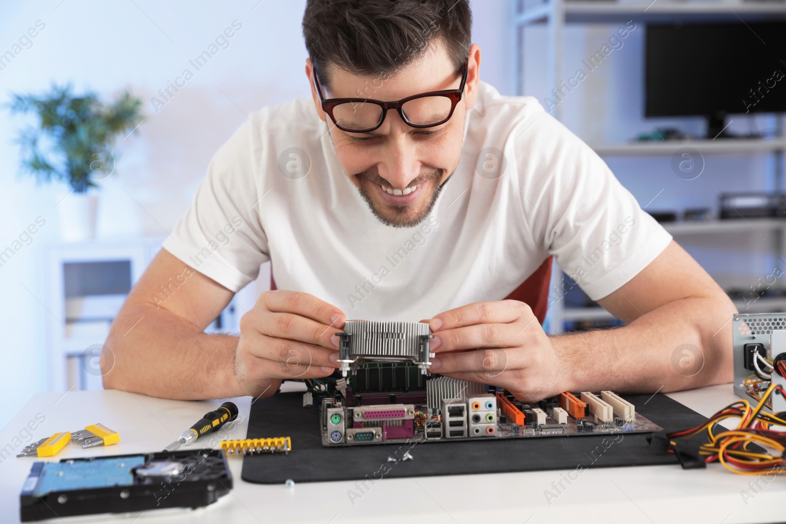 Photo of Male technician repairing motherboard at table indoors