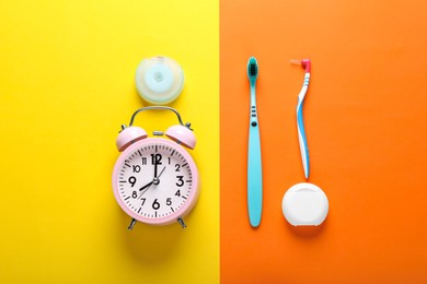 Dental floss, toothbrushes and alarm clock on color background, flat lay
