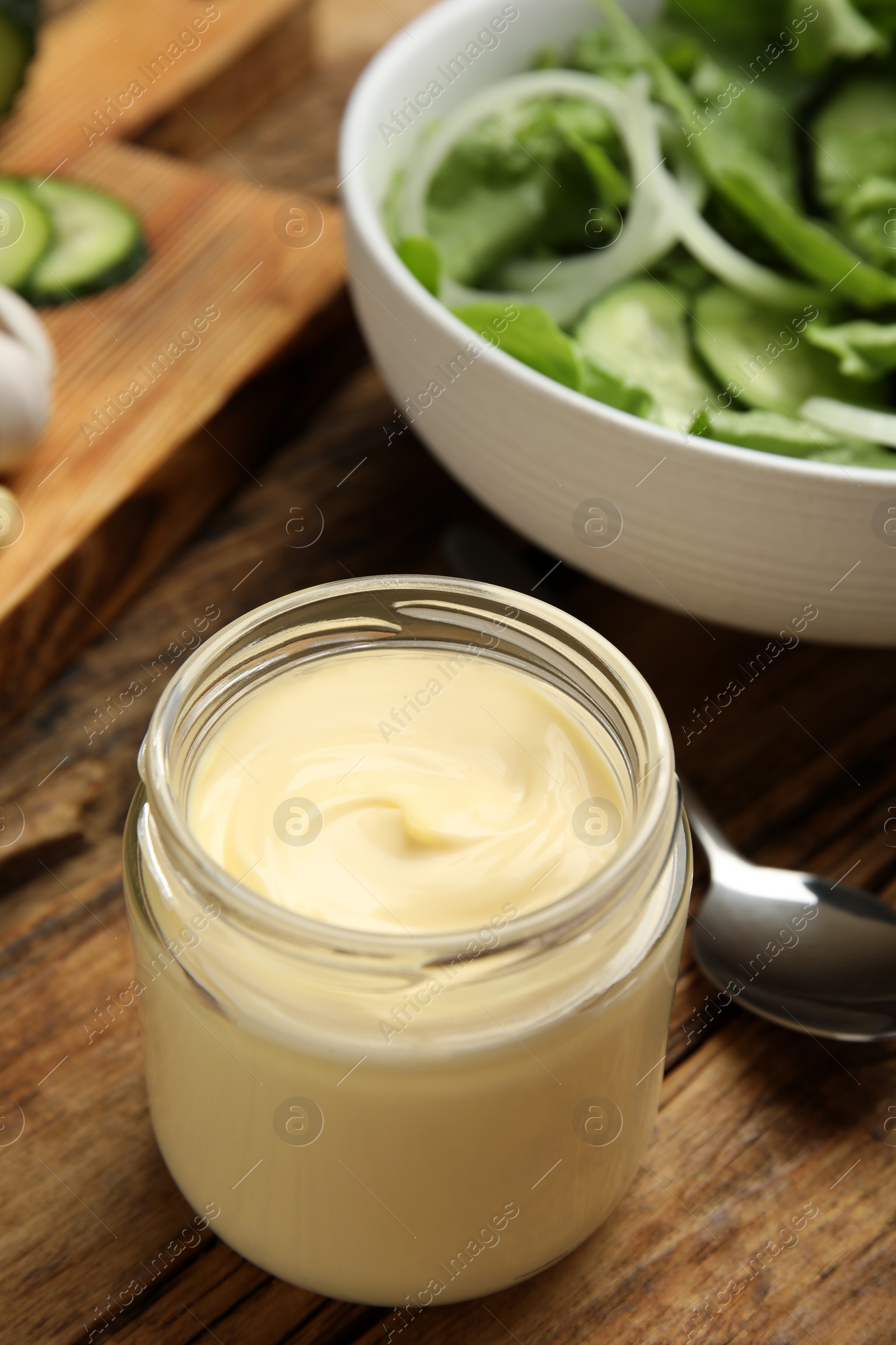 Photo of Jar of delicious mayonnaise and salad on wooden table