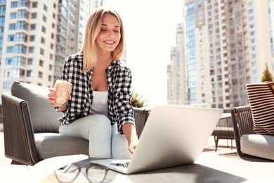 Beautiful woman with laptop and coffee at outdoor cafe