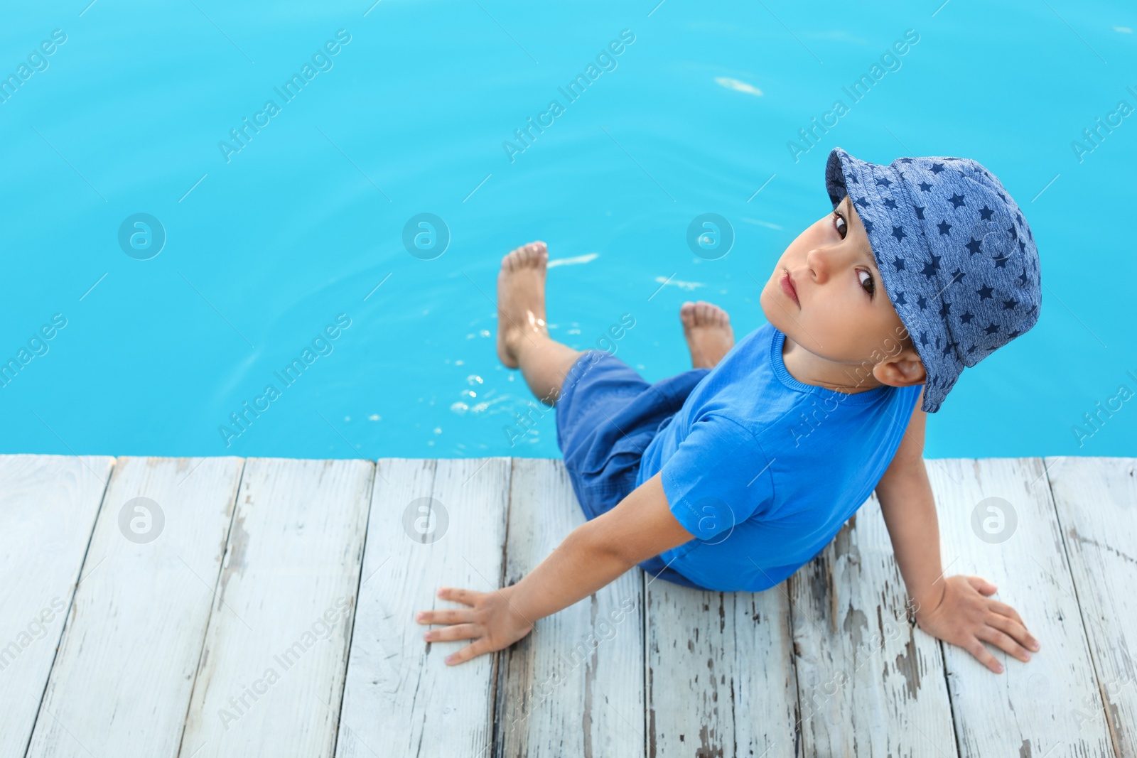 Photo of Little child near outdoor swimming pool. Dangerous situation