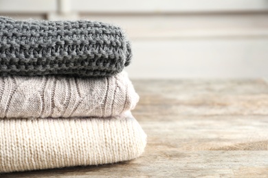 Photo of Stack of warm knitted clothes on table