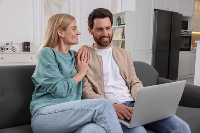 Photo of Happy couple with laptop on sofa at home