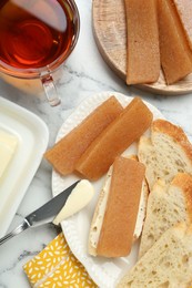 Photo of Delicious quince paste, bread and cup of tea on white marble table, flat lay