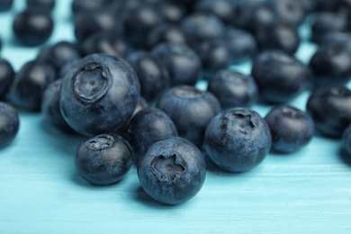 Photo of Pile of tasty blueberries on color wooden table, closeup