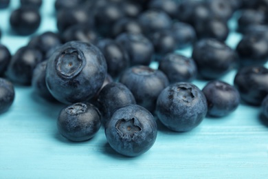 Pile of tasty blueberries on color wooden table, closeup