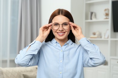 Portrait of smiling woman in stylish eyeglasses at home