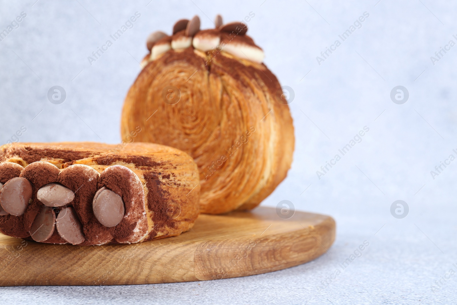 Photo of Tasty puff pastry. Supreme croissants with chocolate chips and cream on grey table, closeup. Space for text