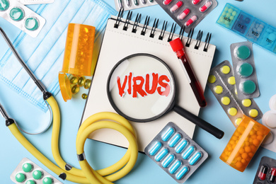 Flat lay composition with word VIRUS and medicines on light blue background