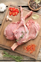 Photo of Fresh tomahawk beef cuts and spices on wooden table, top view