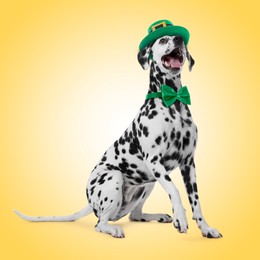 Image of St. Patrick's day celebration. Cute Dalmatian dog with leprechaun hat and green bow tie on yellow background